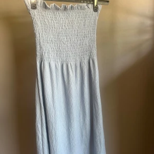 Ljusblå smockad klänning H&M XS - Supersöt ljusblå långklänning från H&M i storlek XS. Klänningen är axelbandslös med smock upptill och har en lätt rynkad kjol. Perfekt för varma dagar och enkel att styla med sneakers eller sandaler. Det är en klänning men går utmärkt att använda även som kjol! Skriv om ni har frågor eller vill va mer bilder💕