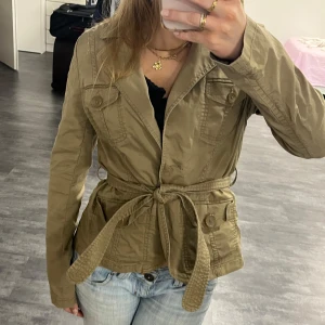 Khaki utilityjacka med bälte - Snygg khaki jacka med bälte i midjan. Ljusgrön eller khaki jeansjacka / safari jacka. Saknar knappar framtill så den kan bara knytas (bild 4).