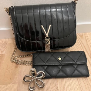 Äkta valentinoväska med tillhörande accessoarer  - Säljer en äkta valentinoväska med både kort handtag och kedje-axelrem. Plånbok och hårklämma i form av en blomma tillkommer om inte annat önskas, i så fall skriv till mig