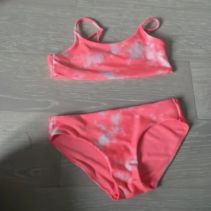 Rosa bikini med batikmönster från H&M. - Snygg bikini från H&M i rosa med ljusa batikliknande mönster. Toppen har smala axelband och en sportig, rak modell. Bikinitrosorna är klassiska med medelhög midja. Perfekt för strandhäng eller poolparty!