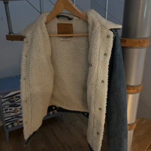 Levi's jeansjacka - Säljer en klassisk blå jeansjacka från Levi's Premium med mjukt vitt teddyfoder på insidan och kragen. Jackan har raka linjer, knappar framtill och är perfekt för kyligare dagar. En ikonisk look som alltid är rätt. Knappt använd därför säljs den nu. Nypris 1500kr 