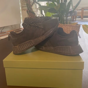 Svarta Adidas NMD sneakers - Säljer ett par helsvarta Adidas NMD sneakers med klassiska tre ränder på sidan. Skorna har en chunky sula och ovandel i textil med snörning. Perfekta för dig som gillar en sportig och stilren look. Passar till det mesta och är riktigt bekväma. Inköpta för 1700kr. Storlek 42 och true to size. Välanvända med defekter, bilder finns i DM! 