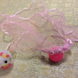 Rosa diadem med slöja och små rosor - Sött rosa diadem med tunn slöja i tyll och små dekorativa rosor framtill. Diademet har en romantisk och lekfull känsla, perfekt för temafester eller maskerader. Slöjan är lång och transparent med ett skirt utseende. Helt ny , finns vit kvar,  barn stlk 