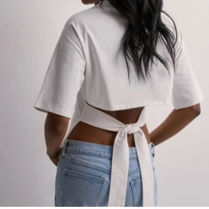 Vit nelly knyt topp - Säljer en fin vit T-shirt med knyt i ryggen från Nelly i storlek xs!! Superfint skick, inga defekter eller något illa, lite minimalt rynkigt skick den kommer i men som såklart går att stryka! Skriv för fler bilder eller tankar/funderingar! 🙌🏼🥹