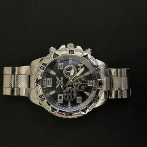 Silverfärgad Quartz klocka - Stilren klocka från Yazole med silverfärgat armband i metall och svart urtavla. Klockan har flera små urtavlor, tydliga siffror och detaljerad boett. Perfekt accessoar för dig som gillar en sportig och modern look.
