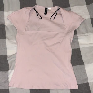 Ljusrosa ribbad topp från H&M Divided - Supersöt ljusrosa ribbad topp från H&M Divided med korta ärmar och fyrkantig halsringning. Toppens material är mjuk bomull och den har en slim passform som sitter snyggt. Perfekt att styla med jeans eller kjol för en trendig look.