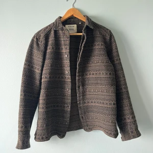 Mönstrad brun skjorta från Anerkjendt - Säljer en brun overshirt från Anerkjendt i storlek M. Skjortan har ett mönster i mörkbruna färger, och materialet känns lite tjockare. Sitter mer som S än M. Axelbredd: 45, längd: 65