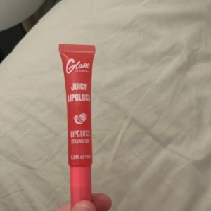 Juicy Lipgloss Strawberry Glam - Juicy Lipgloss från Glam of Sweden i smaken Strawberry. Kommer i en smidig tub med rosa och röd design. Ger läpparna en glansig finish och en hint av färg. Perfekt för dig som vill ha en fräsch och söt look med jordgubbsdoft.