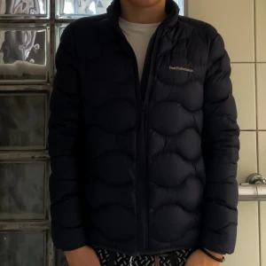 Peak Performance Helium Down Jacka - Säljer nu denna Blue Shadow Peak Performance Jacka som ej säljs längre, köpt för 2000 KR och använd max 3 gånger, den är helt nyskick. Det är storlek 170 CM i junior som motsvarar storlek XS/S för den är stor i storleken, jag är 180 CM på bilden. 