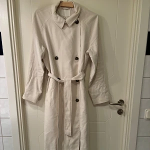 Trenchcoat i nydkick - Knappt använd så skicket är väldigt bra. Stl S. Yttertyg i härlig viskosblandning. Säljes pga har en annan trenchcoat som jag använder mer.