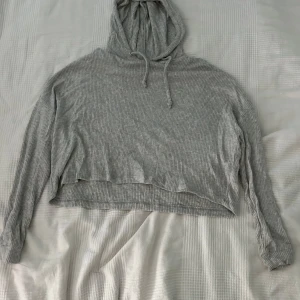 Grå ribbad hoodie från BikBok - Säljer en supermysig grå ribbad hoodie från BikBok. Den har en avslappnad passform med långa ärmar och en croppad stil. Knappt använd.