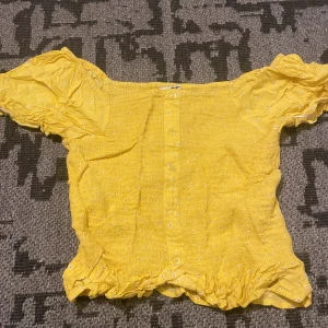 Gul blus från Hampton Republic - Säljer en superfin gul blus från Hampton Republic. Den har korta puffärmar och ett sött blommönster. Blusen är smockad och har knappar framtill. Perfekt för sommardagar eller en festlig tillställning! 🌼