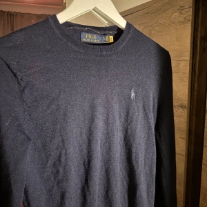 Stickad Ralph Lauren tröja  - Säljer en stilren mörkblå tröja från Polo Ralph Lauren i slim fit. Tröjan har långa ärmar och är tillverkad i ett mjukt material. Storlek XS men sitter som S. 