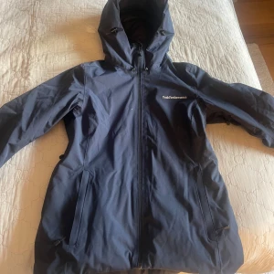 Marinblå jacka från Peak Performance - Säljer denna marinblåa jacka från Peak Performance med huva och dragkedja. Perfekt för kyligare väder eller skidåkning. Kommer inte till användning längre och är i mycket bra skick!