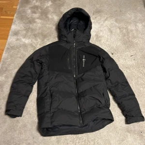 Svart vinter jacka sail racing - Snygg svart vinter jacka från Sail racing med huva och dragkedja. Perfekt för kalla vinterdagar. Jackan är i ett toppen skick och priset är ej hugget i en Sten, hör av er vid funderingar😄