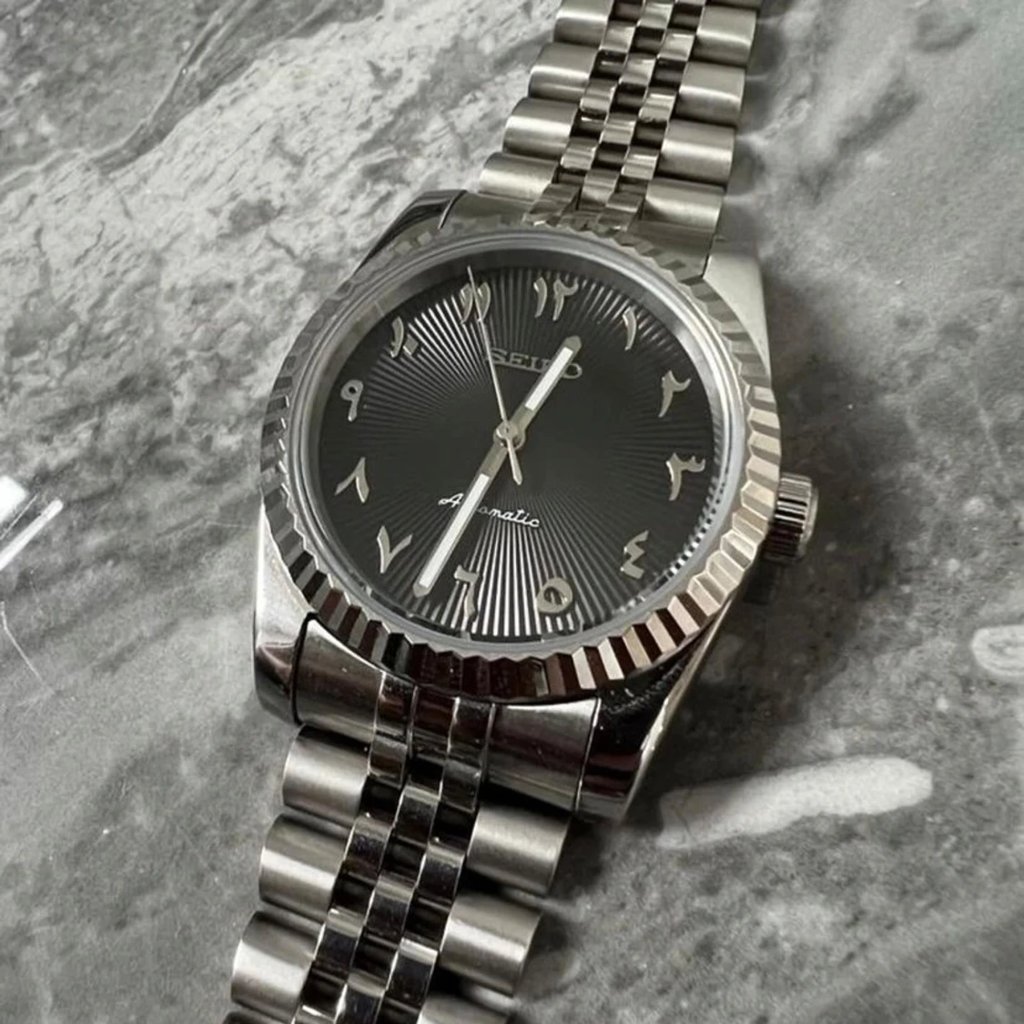 Silverfärgad seiko klocka med arabiska siffror