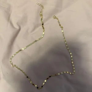 Guldfärgat halsband - Elegant guldfärgat halsband med en glittrig yta som reflekterar ljuset vackert. Perfekt för att lägga till en touch av glamour till din outfit.