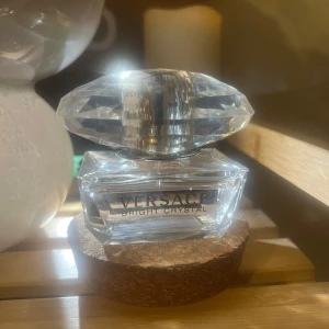 Versace Bright Crystal Parfym - Elegant parfymflaska från Versace med namnet Bright Crystal. Flaskan är genomskinlig med en stor, kristalliknande kork som ger ett lyxigt intryck. Perfekt för den som vill ha en doft med stil, den luktar väldigt uppfriskande och är väldigt stark i doften så det räcker gott och väl med 1 sprut☺️Parfymen är använd men är nästan full!! Köper du denna parfymen får du även halva priset på den andra parfymen från Marc Jacobs jag säljer 😍😍