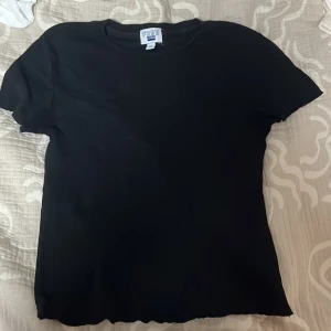 Svart t-shirt från Free x Cotton On - Säljer en klassisk svart t-shirt från Free x Cotton On. Den har en enkel design med korta ärmar och rund hals. Perfekt basplagg för alla tillfällen.