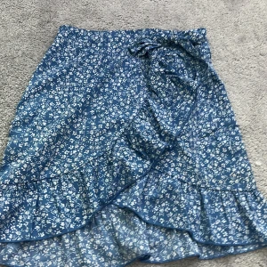 Blå blommig kjol   - Är osäker på storleken men jag som har xs-s kan ha den, är nog från shein men har använt den 2-3 gånger 💕 bra skick den har en dragkedja och man kan knyta rosetten hur man vill 