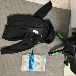  Polo Ralph Lauren - Snygg svart hoodie från Polo Ralph Lauren med dragkedja och det klassiska broderade logotypen på bröstet. Perfekt för en stilren och bekväm look. Passar bra till både jeans och joggers. Passar Xs/S