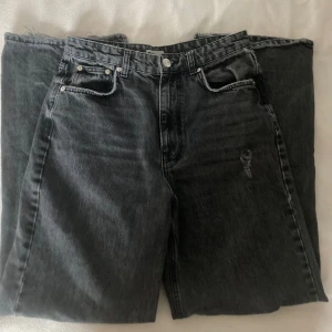 Gråa jeans från Gina tricot  - Snygga gråa jeans från Gina Tricot i storlek 40. De har en klassisk femficksdesign och slitna detaljer på knäna för en trendig look. Perfekta för en avslappnad stil.