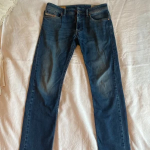 Blå jeans från Diesel - Snygga blå jeans från Diesel med klassisk femficksdesign och knappgylf. Perfekta för en avslappnad stil med en modern touch. Passar till det mesta i garderoben.