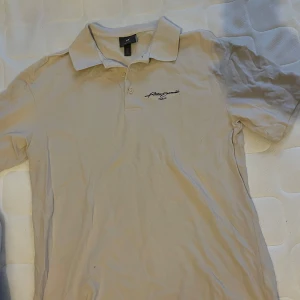 Beige pikétröja från H&M - Säljer en beige pikétröja från H&M med broderad text 'Paris' på bröstet. Tröjan har en klassisk krage och korta ärmar, perfekt för en avslappnad stil. PM vid frågor pris kan diskuteras.