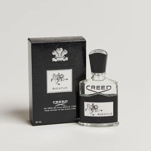 Creed Aventus 100ml Parfym - Exklusiv Creed Aventus parfym i elegant glasflaska med svart etikett och lock. Känd för sin kraftfulla och maskulina doft, perfekt för den självsäkra mannen. 