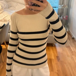 Randig ribbad tröja - Säljer en snygg ribbad tröja med svart och beige randigt mönster. Tröjan har en offshoulder-design och långa ärmar, perfekt för en stilren look. Passar bra till både jeans och kjol. Lite smutsig men går att tvätta bort i tvätt💗