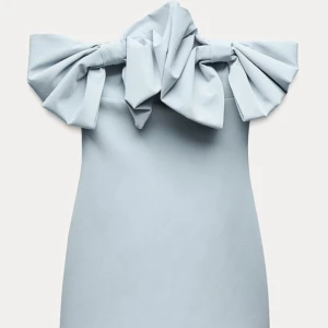 Ljusblå klänning med rosett från Zara - Snygg ljusblå axelbandslös klänning med en stor rosett framtill. Perfekt för en elegant look. Klänningen har en dragkedja bak för enkel påklädning. Helt ny med prislapp kvar, säljes då den tyvärr inte passa. Slut på hemsidan!!🌟💕