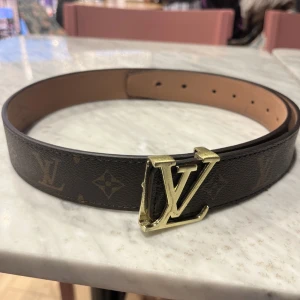 Brunt bälte med guldspänne - Snyggt brunt bälte med ett iögonfallande guldspänne. Bältet har ett klassiskt mönster och är perfekt för att ge en lyxig touch till din outfit.