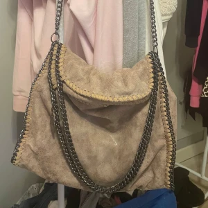 Stella mc cartney - Stella McCartney liknande. Snygg beige axelväska med coola kedjedetaljer. Väskan har en dragkedja på baksidan och en rymlig insida.