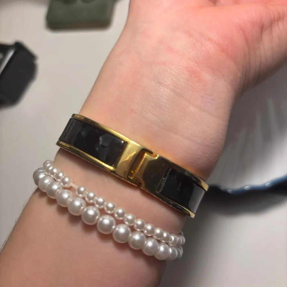 Snygg guldfärgad klocka med svart armband och glittrande stenar runt urtavlan. Perfekt accessoar för att lyfta din stil. Urtavlan är svart med guldfärgade detaljer. Fungerar!. Asusteet.