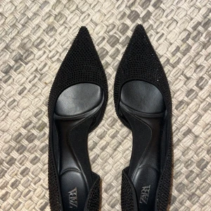 Svarta glittriga pumps/klackar från Zara - Eleganta svarta klackskor från Zara med spetsig tå och klack. Skorna är täckta med glittriga stenar. Perfekta för en kväll ute eller en speciell tillställning. Helt nya, endast testade.