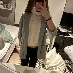 Grå kavaj - Snygg grå kavaj med trekvartsärm, perfekt för en stilren look. Passar bra över en stickad tröja eller blus. Enkel och elegant design som funkar till många tillfällen. Superskönt material.