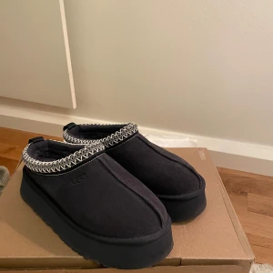 UGG TAZZ - Mocka mörkblå ugg tazz. Köpta förra året använda 1-2 gånger. Säljer då jag inte fått någon användning av dom.  Originalkartong har jag tyvärr slängt men skickas i annan kartong. 