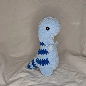 Virkad trex🦖 - Höjd: 18cm Bred: 11cm Det är en egenvirkad trex som är gjord på fluffigt garn som är 100% polyester 