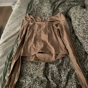 Beige långärmad topp från H&M - Säljer en enkel och stilren beige långärmad topp från H&M Basic. Perfekt för vardagsbruk med en skön passform. Materialet är mjukt och bekvämt, vilket gör den idealisk för både höst och vår. Toppen är i bra skick och redo för en ny ägare!