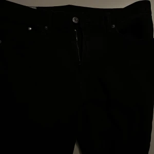 Svarta slim fit byxor från H&M - Säljer ett par svarta slim fit byxor från H&M. De är i bra skick och perfekta för både vardag och fest. Byxorna har en dragkedja och knapp framtill. De är tillverkade i ett bekvämt material som sitter snyggt på kroppen.