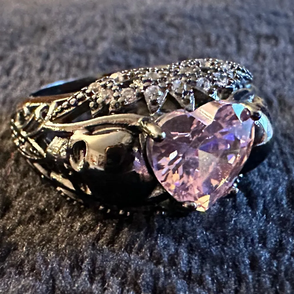 Den här ringen har allt - glittrande cubic zirconerer och en rosa hjärtformad kristall omgiven av dödskallar. 925 sterling silver. Ca 1,8 cm i innerdiameter. Helt makalöst unik, absolut nyskick. Dark romance Säljs då jag inte använder ringar längre. . Accessoarer.