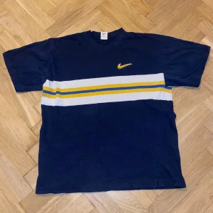 Blå t-shirt från Nike - Ovanlig vintage Nike tröja i perfekt skick. Den har korta ärmar och är perfekt för en avslappnad stil. Nike-loggan är broderad i gult på bröstet. Inga fläckar eller märken.