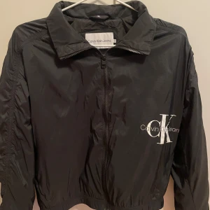 Svart vindjacka från Calvin Klein Jeans - Säljer en snygg svart vindjacka från Calvin Klein Jeans. Storlek 14 år men sitter som en Xs (möjligtvis liten S).