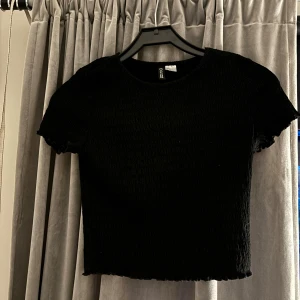 Svart croppad topp från H&M Divided - Säljer en svart croppad topp från H&M Divided. Den är kortärmad och har en enkel, stilren design. Perfekt för både vardag och fest! 🖤