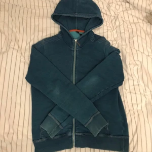 Nudie Hoodie - Säljer en as fet Nudie hoodie i storlek M. Broderad Nudie logga på ryggen som sträcker sig runt till axlarna. Hoodien har en riktigt shysst fade efter alla år. Skicket är bra förutom några små fläckar som knappt syns men därav priset. Kontakta mig vid frågor/funderingar!