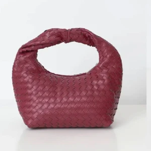 Vinröd flätad handväska - Snygg vinröd handväska med flätat mönster och dragkedja. Perfekt accessoar för att ge din outfit en trendig touch. Den är i helt nytt skick!