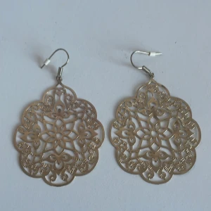 Guldiga örhängen med utskuret mönster - Snygga guldiga örhängen med ett intrikat utskuret mönster som ger en elegant touch. Perfekta för att lyfta vilken outfit som helst med sin unika design.