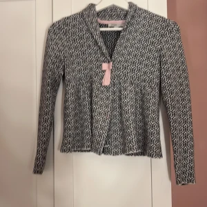 Mönstrad kofta från MyWear - Säljer en snygg mönstrad kofta från MyWear i svart och vit. Koftan har långa ärmar och en stilren design med ett diskret mönster. Perfekt för att hålla sig varm och stilig under kyligare dagar.