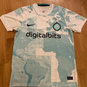 Vit och ljusblå fotbollströja från Inter Milan  - Snygg fotbollströja med världskarta i ljusblått och vitt. Jag säljer tröja pga att den var lite för liten för mig