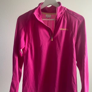 Rosa långärmad tröja från Craft - Säljer en snygg rosa långärmad tröja från Craft. Perfekt för träning med dragkedja framtill och bekväm passform. Tröjan har en sportig look och är gjord i ett lätt och andningsbart material. Använd fåtal gånger. 